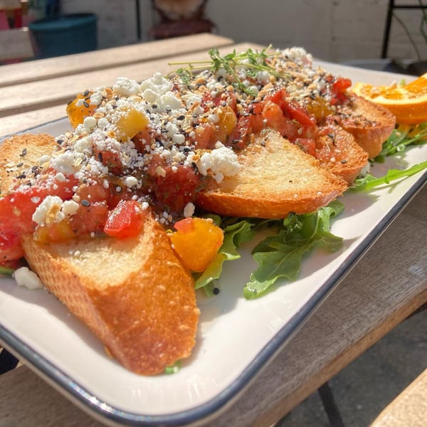 Milque Toast's bruschetta with diced tomatoes, feta, seeds, and herbs on toasted bread.