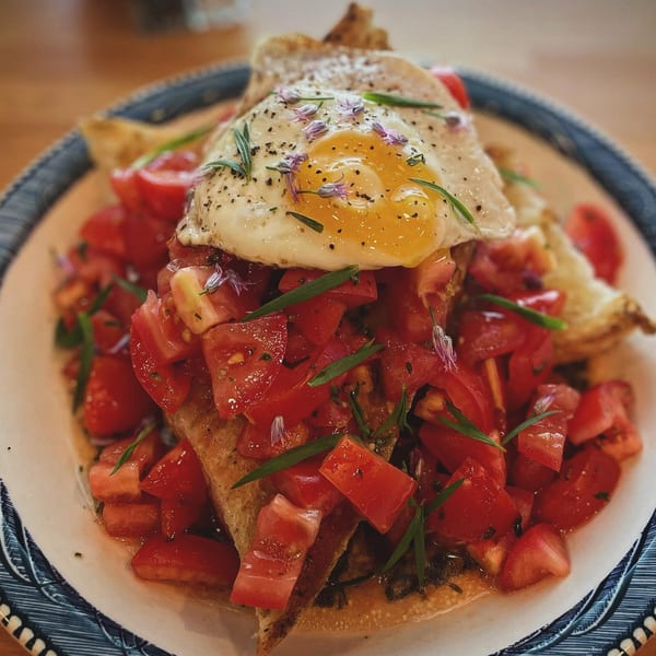 Milque Toast's breakfast dish with a fried egg, diced tomatoes, and herbs on toast.